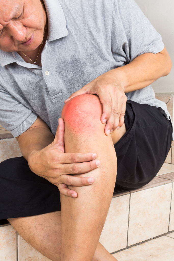 elder man touching his swollen knee