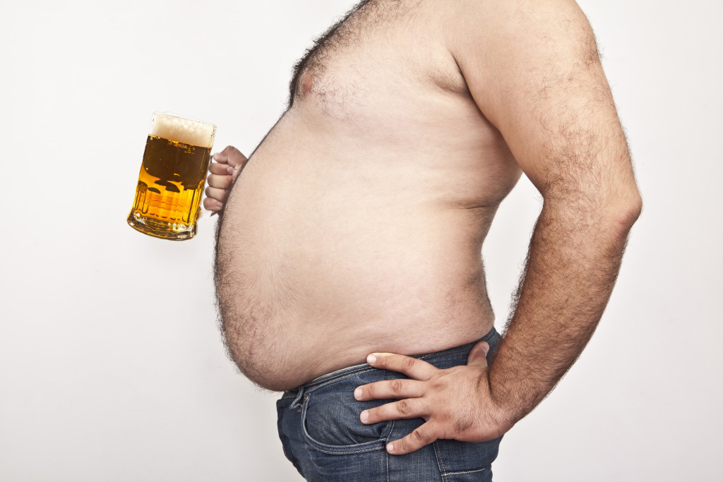 A obese man carrying a beer mug