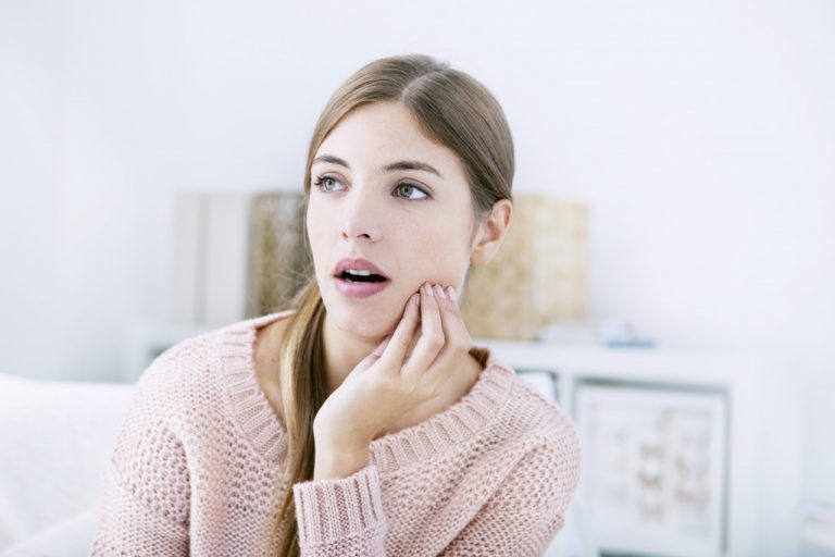 A woman holding her jaw