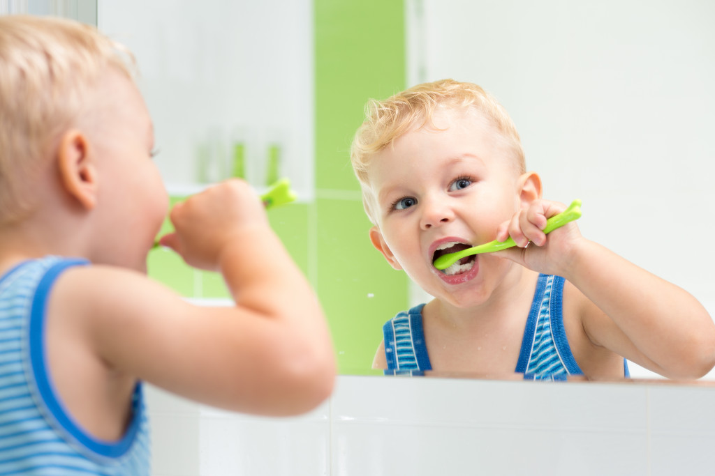 A child brushing his teeth with a green toothbrush