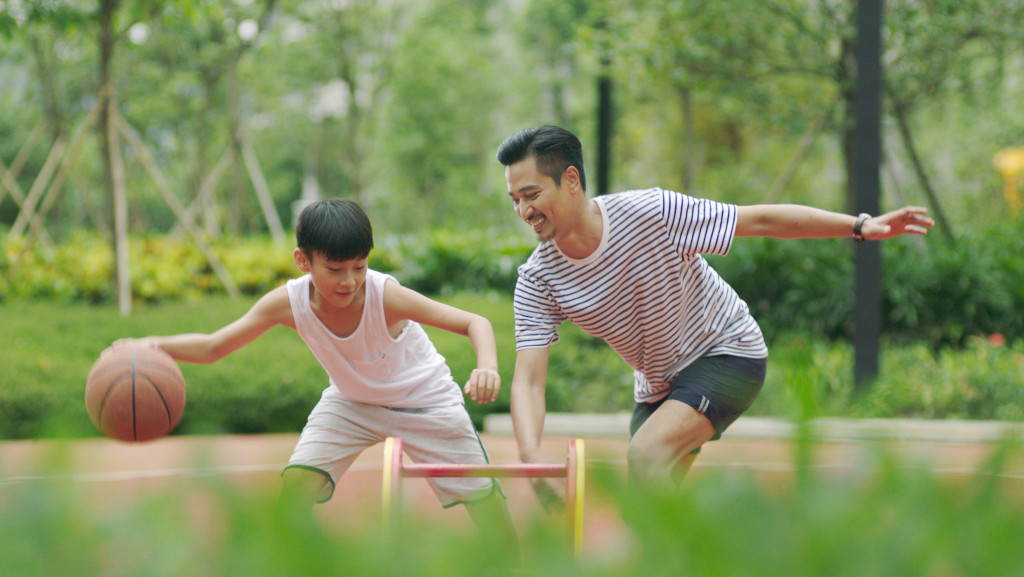 asian father and son playing basketball in the garden in morning