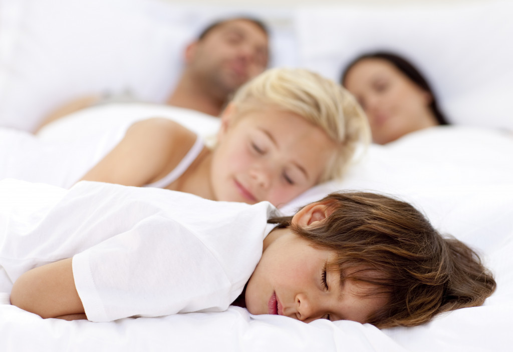 Children sleeping with his parents in a big bed