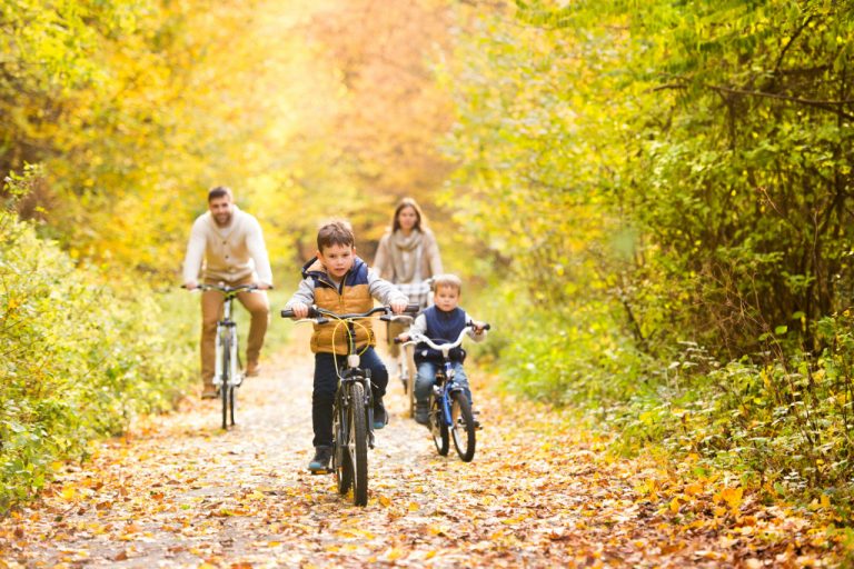 Young family in warm clothes cycling in autumn park