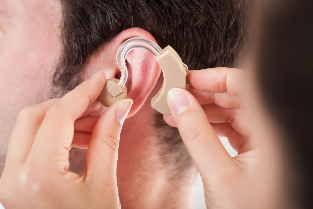 Close-up of a doctor helping a patient to wear a hearing aid.