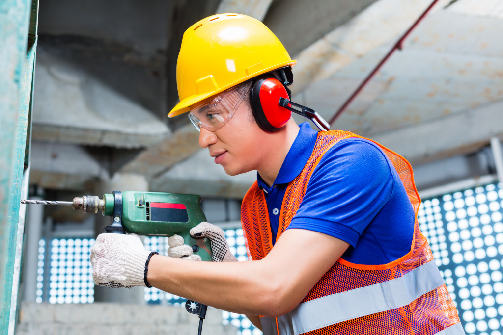a man using earmuffs to protect the ears while drilling