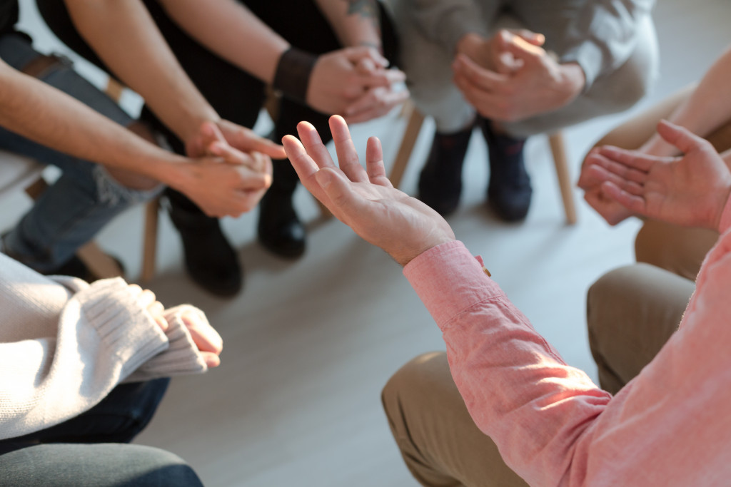 Photo of the hands of a therapist while talking to a group of young people in a session