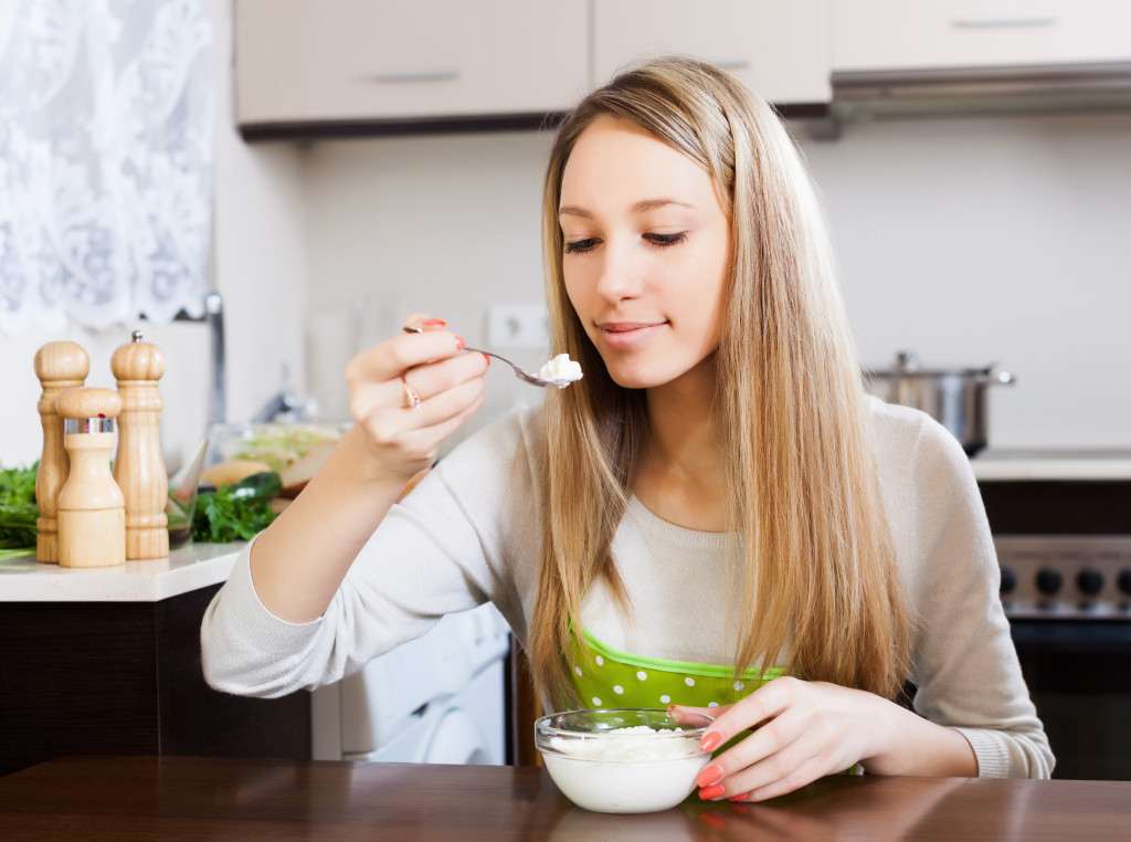 a young woman about to eat a spoonful of yogurt from a bowl
