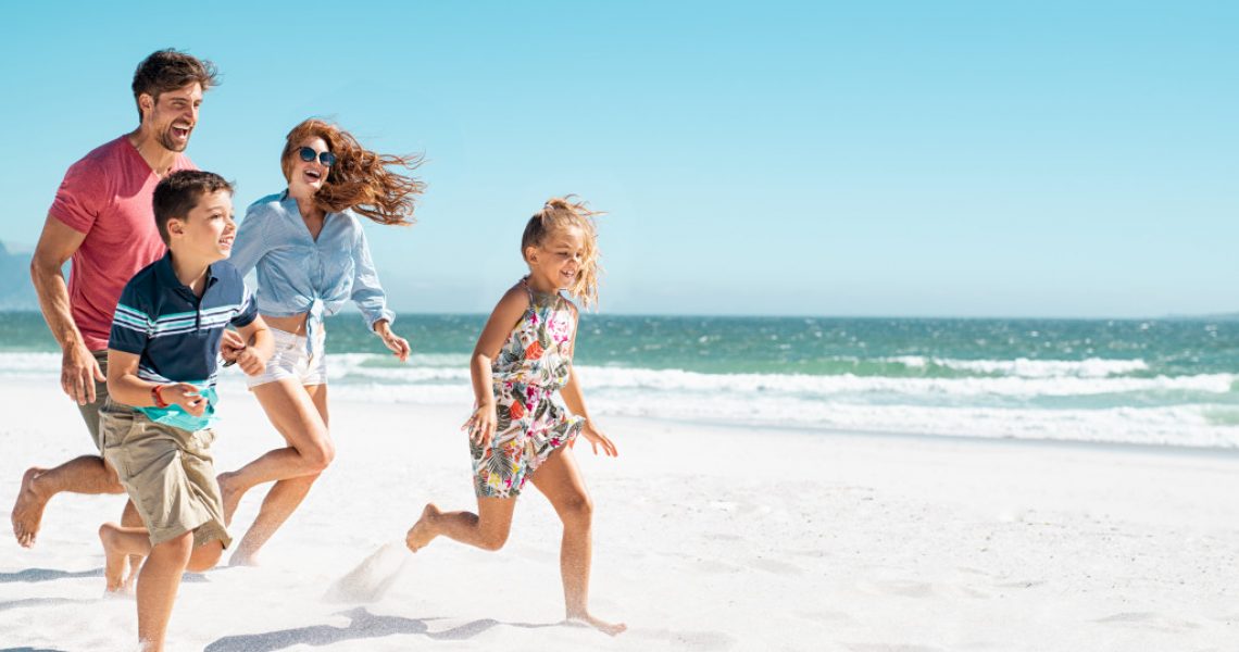 cheerful young family running on the beach